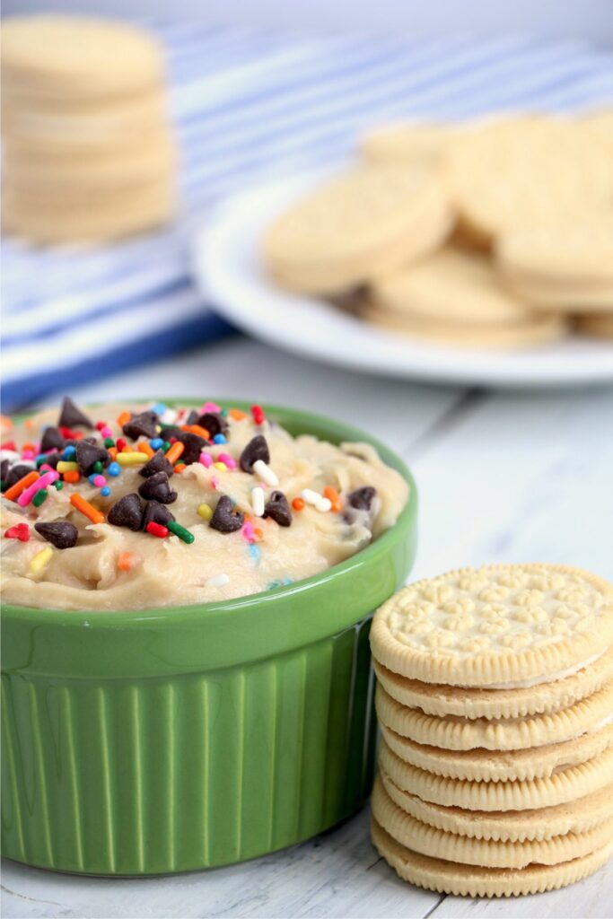 Closeup shot of ramekin full of cookie dough dip next to stack of cookies