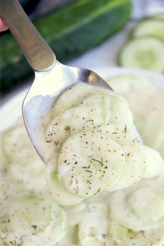 Closeup shot of spoonful of creamy cucumber salad with miracle whip