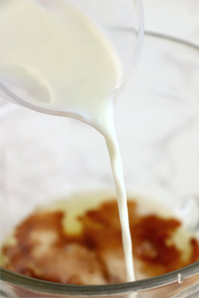 Milk being poured into bowl of eggs and vanilla
