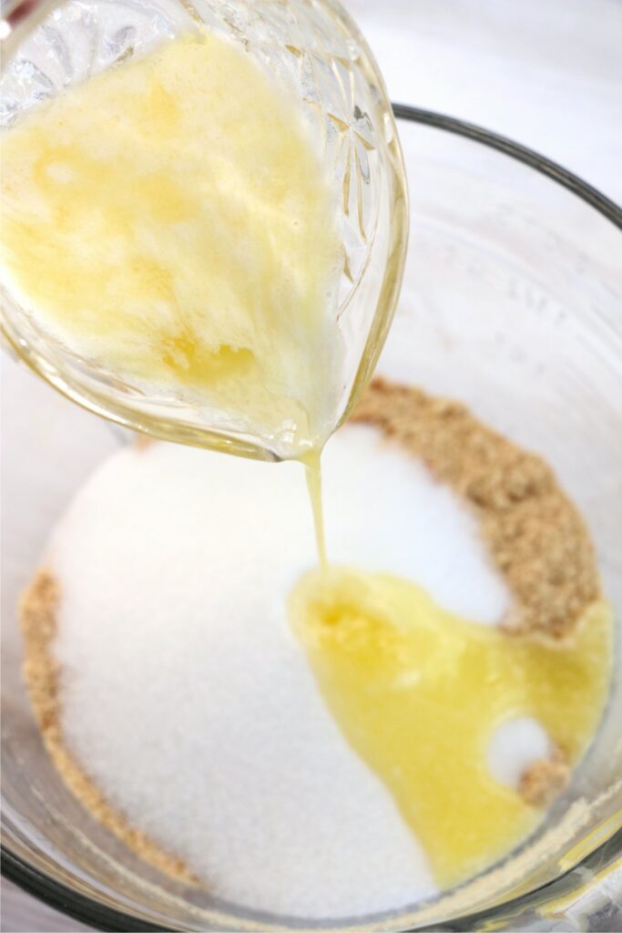 Mleted butter being poured into bowl of crushed Nilla wafers and sugar