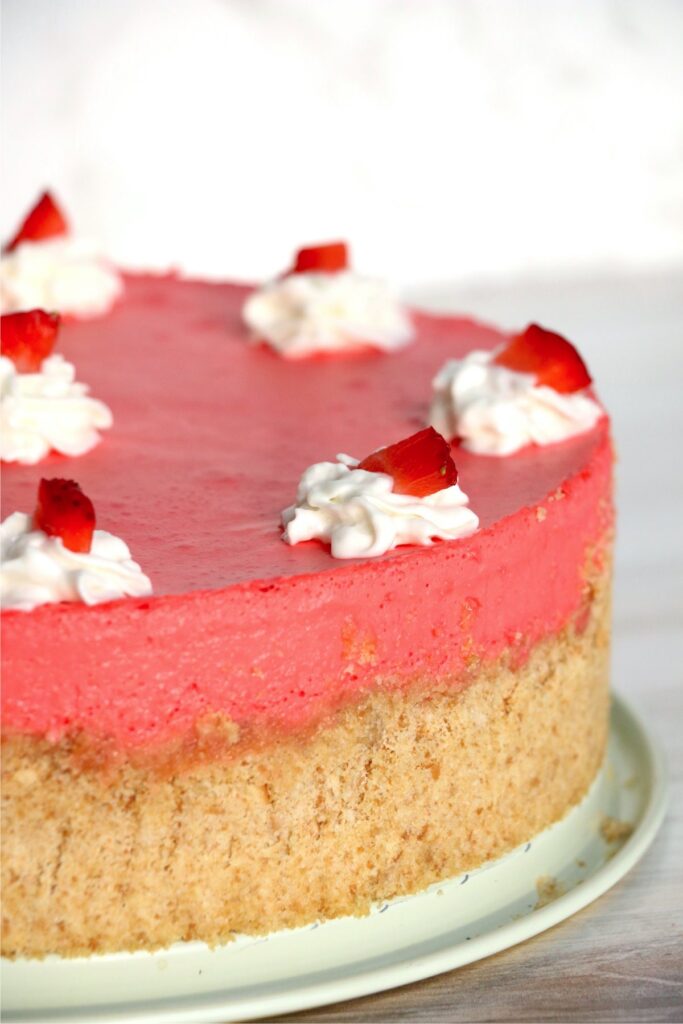 Closeup profile shot of strawberry jello cheesecake decorated with whipped craem and strawberry slices