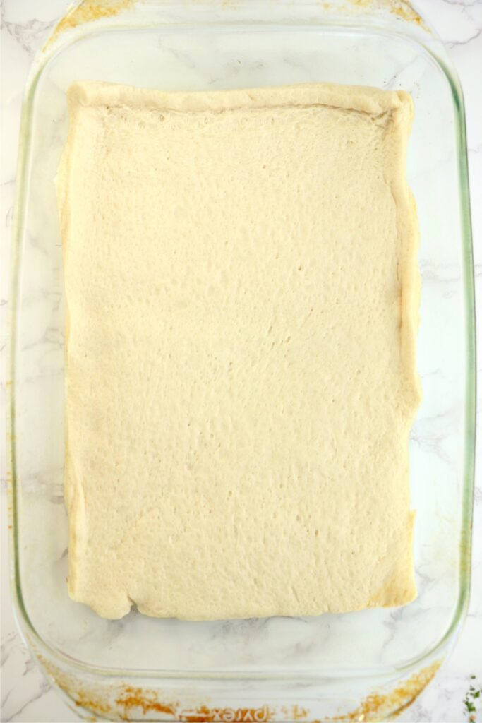 Overhead shot of pizza dough spread out in the bottom of a baking dish