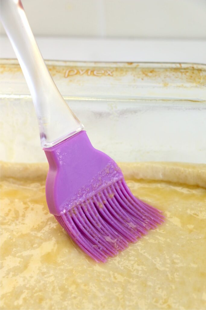 Closeup shot of butter bing brushd onto pizza dough