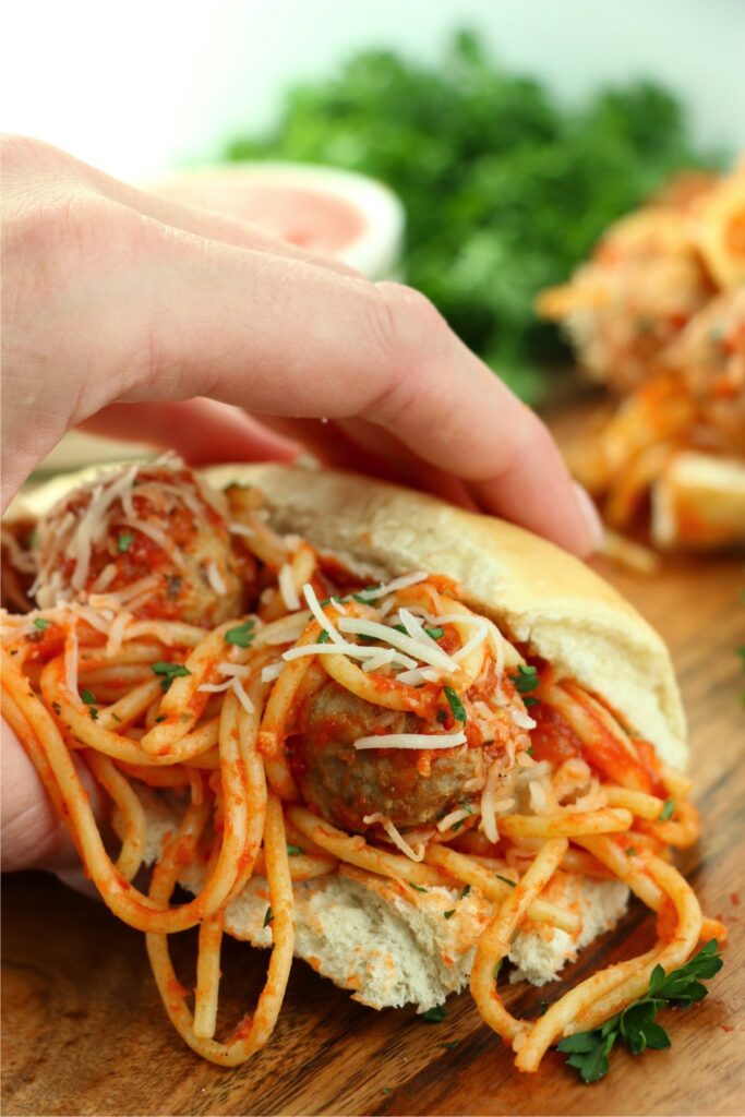 Closeup shot of hand holding spaghetti stuffed sub