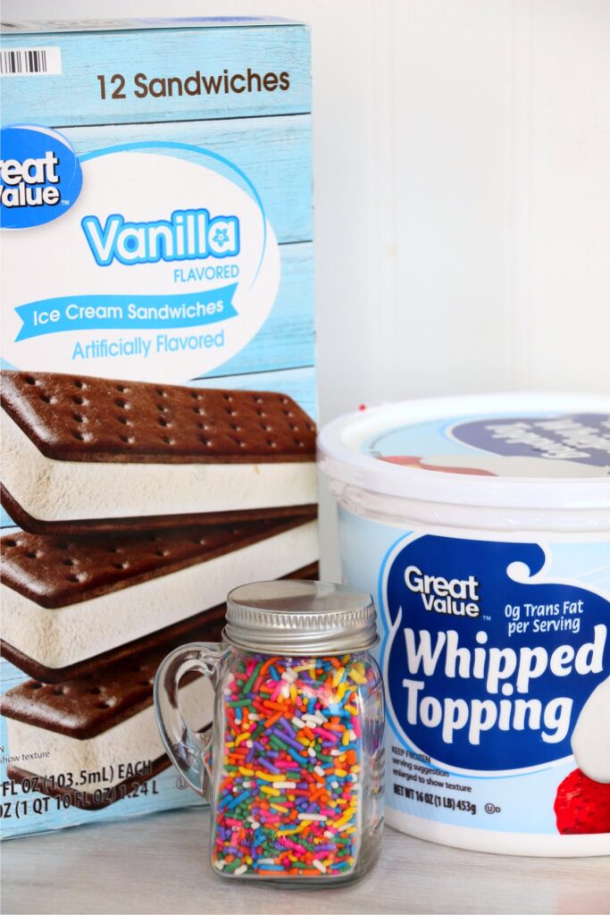 Packages of ice cream sandwiches, whipped toping, and sprinkles on table