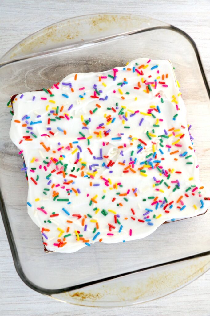 Overhead shot of ice cream sandwiches topped with whipped cream and sprinkles in a baking dish