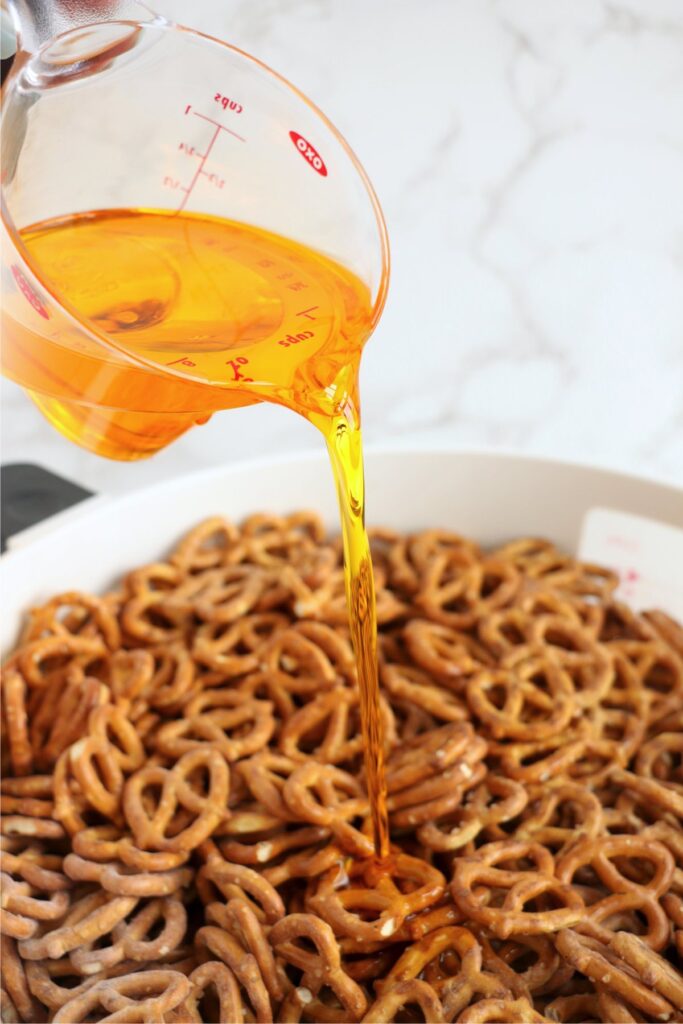 Pocorn oil being poured over pretzels and seasonings