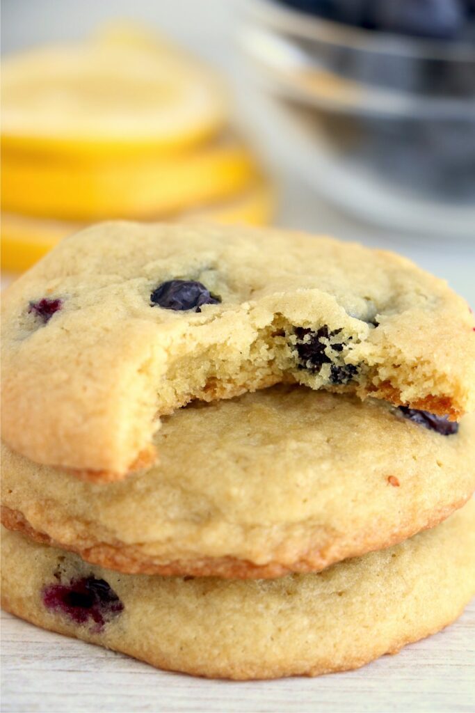 Closeup shot of lemon blueberry cookies stacked atop one another with bite taken out of top cookie