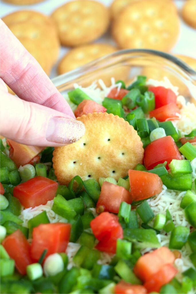 Closeup shot of cracker being dipped into seafood cheese dip