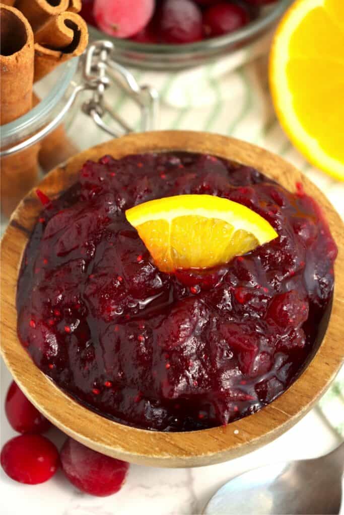 Closeup shot of bowlful of cranberry sauce garnished with orange slice in wooden bowl