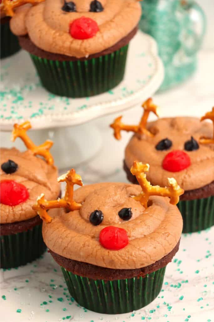Chocolate reindeer cupcakes in front of cake stand with more cupcakes