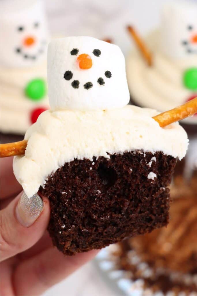 Closeup shot of hand holding snowman cupcake cut in half