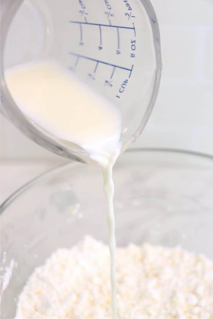 Closeup shot of milk being poured into bowl of creamed sugar and butter