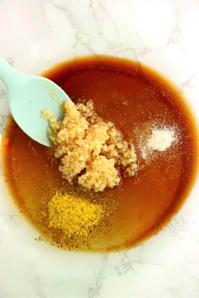Closeup overhead shot of honey, garlic, lemon pepper seasoning, salt, and lemon juice in a bowl