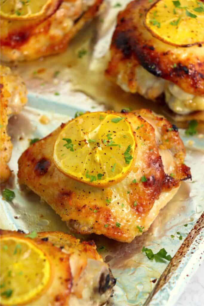 Closeup shot of cooked honey garlic lemon pepper chicken thighs on baking sheet lined with foil