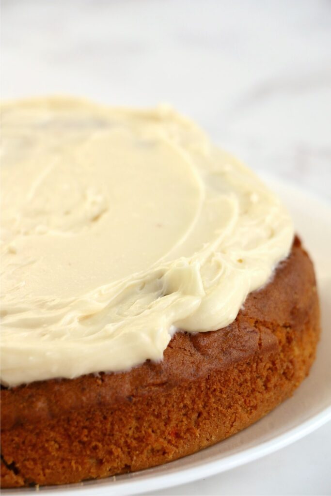 Closeup shot of carrot cake layer topped with cream cheese frosting