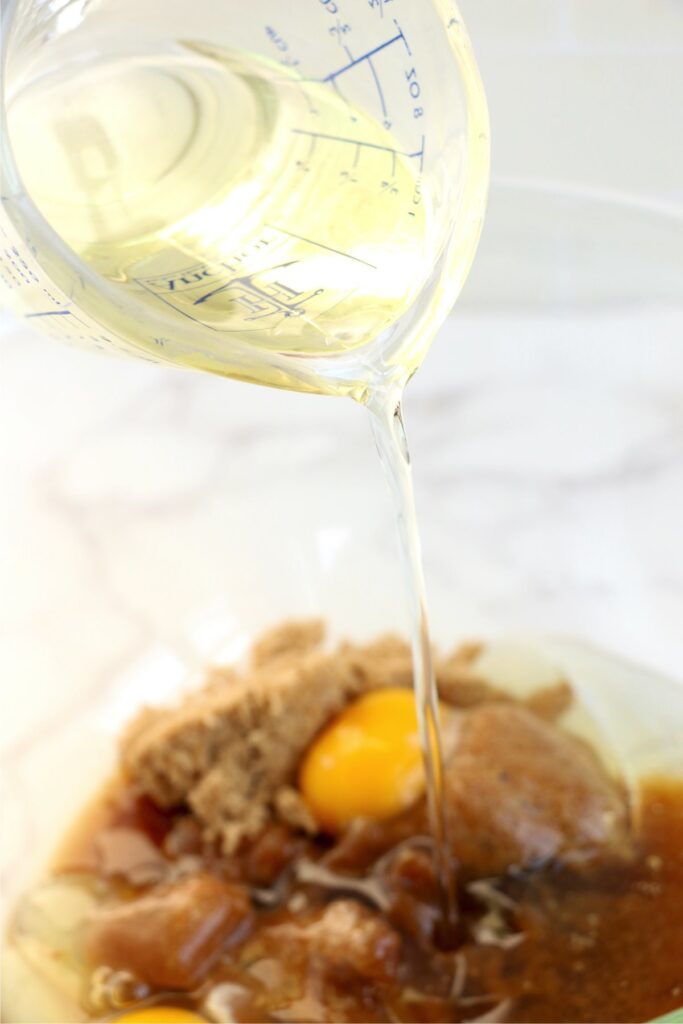 Oil being poured into mixing bowl with butter, sugar, and eggs.