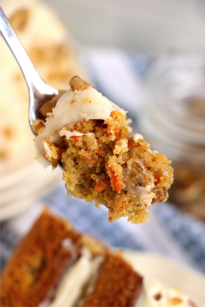 Closeup shot of forkful of air fryer carrot cake over more carrot cake