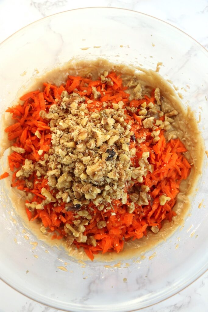 Overhead shot of shredded carrots and nuts in batter