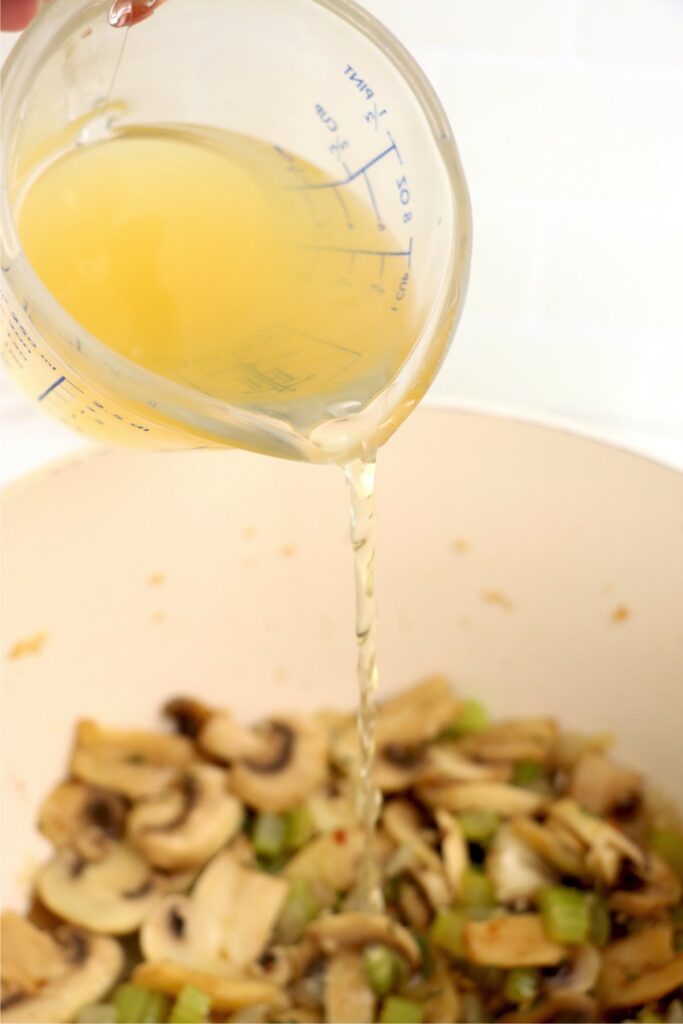 Broth being poured into pot of vegetables