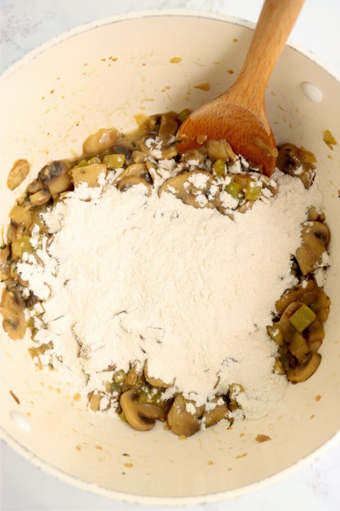 Overehead shot of vegetables and flour in pot.