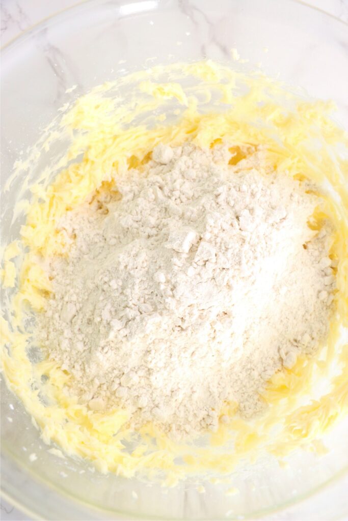 Overhead shot of flour on top of creamed butter and sugar in bowl