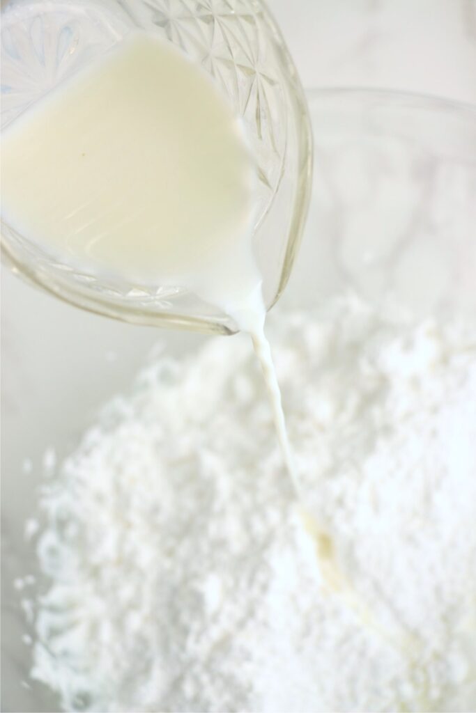 MIlk being poured into bowl of powdered sugar.