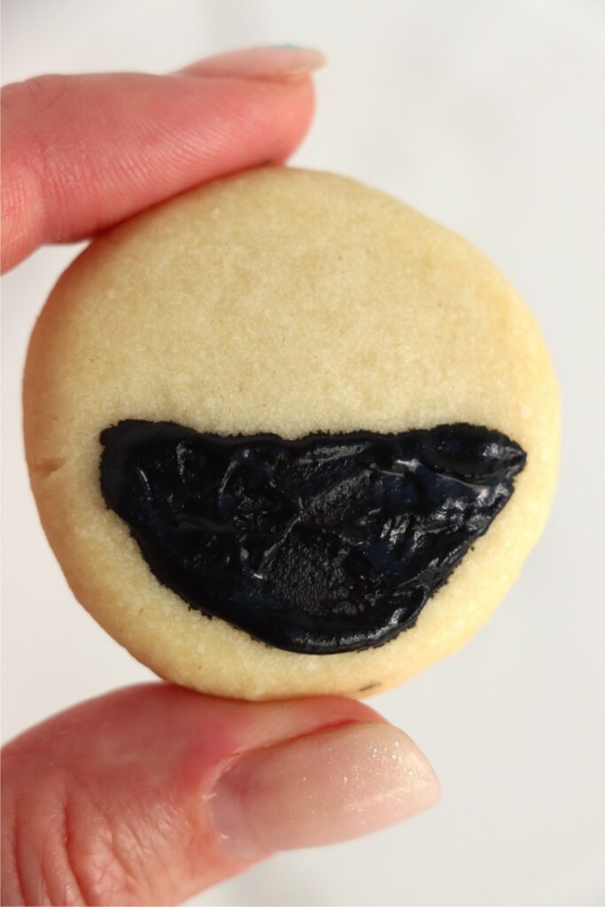 Closeup shot of cookie with black frosting on the botom. 