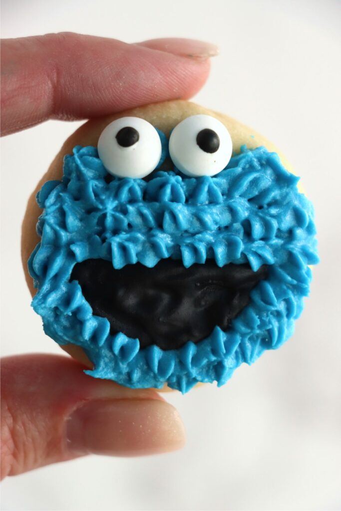 Closeup shot of hand holding Cookie Monster cookie