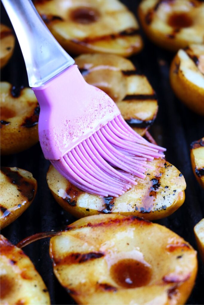 Closeup shot of grilled pears being brushed with brown sugar-cinnamon mixture