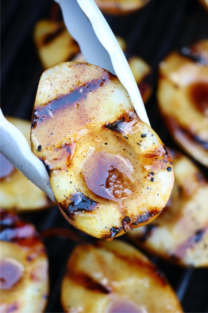 Closeup shot of tongs holding a grilled pear