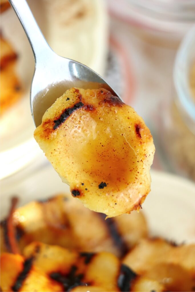 Closeup shot of spoonful of pear over bowl of more grilled pears.