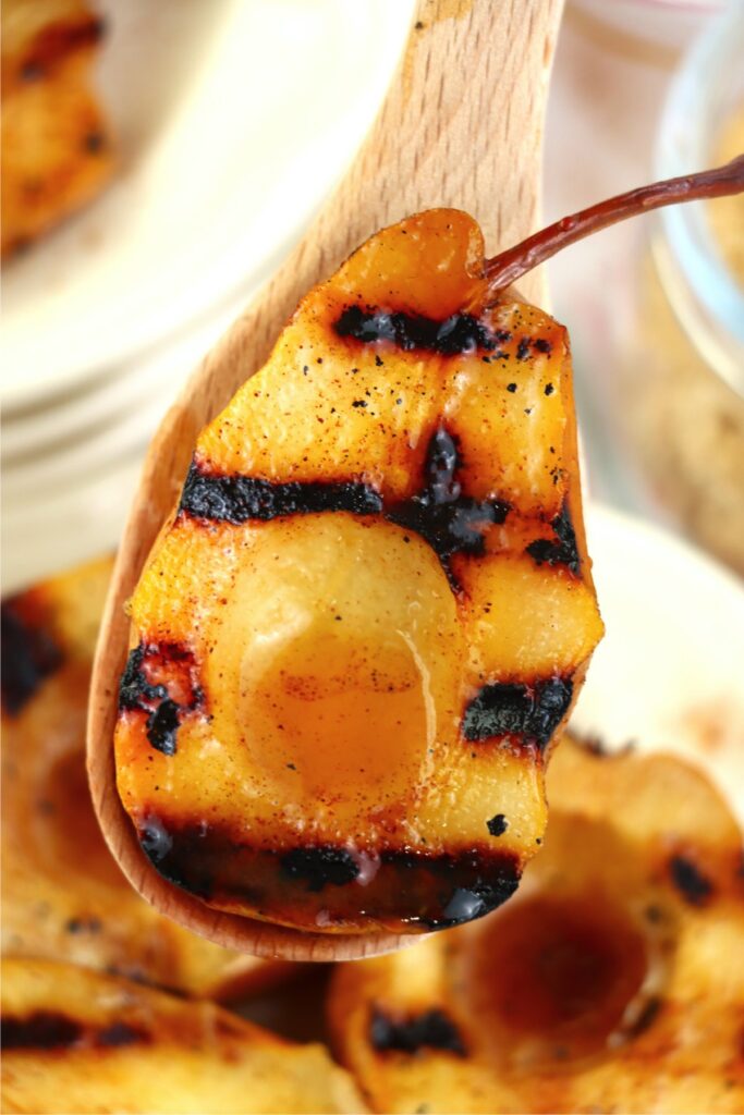 Closeup shot of grilled pear on large wooden spoon