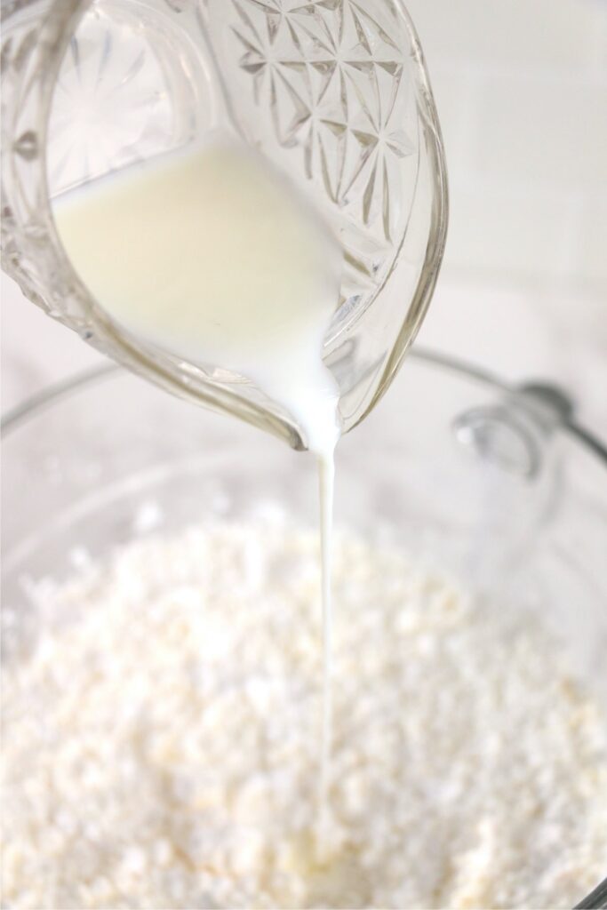 Closeup shot of milk being poured into bowl of butter and powdered sugar