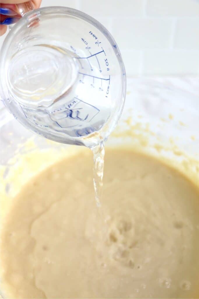 Water being poured into batter in bowl