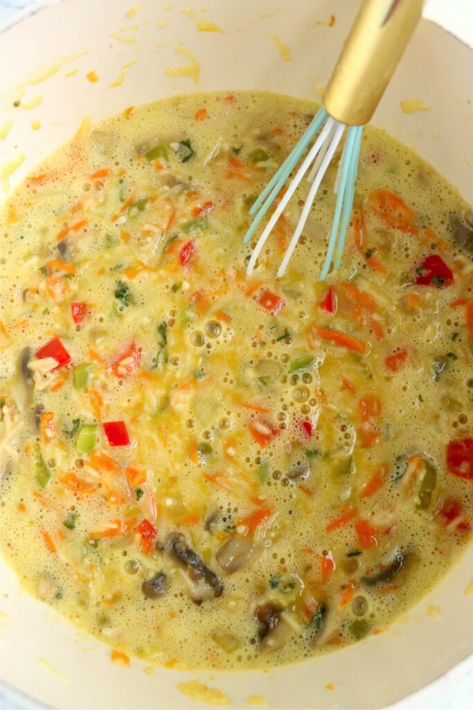 Closeup overhead shot of vegetables, eggs, and cheese mixture in pot