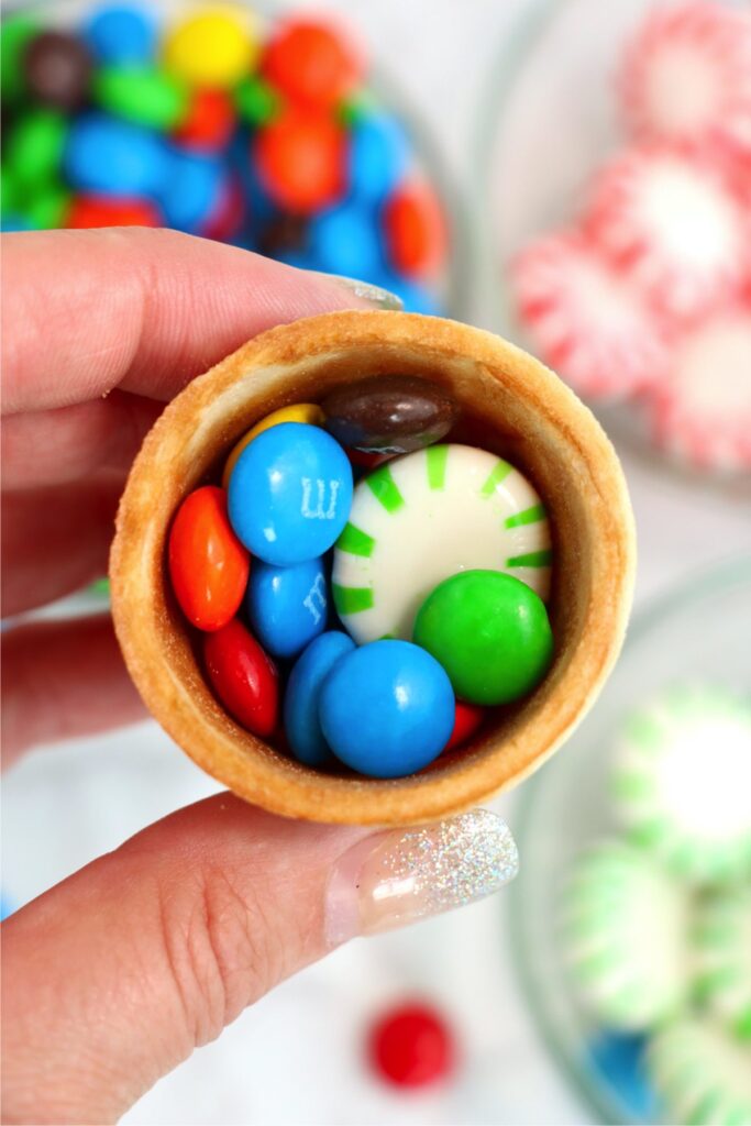 Overhead closeup shot of hand holding sugar cone filled with candies