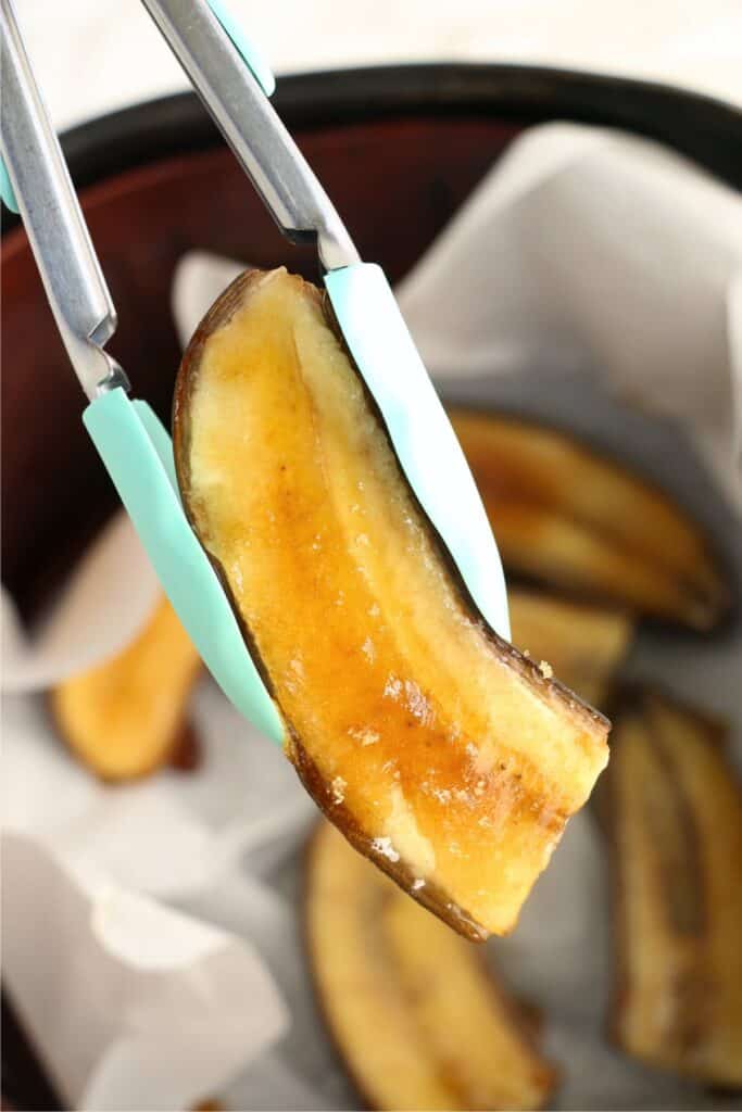 Closeup shot of tongs holding an air fryer banana