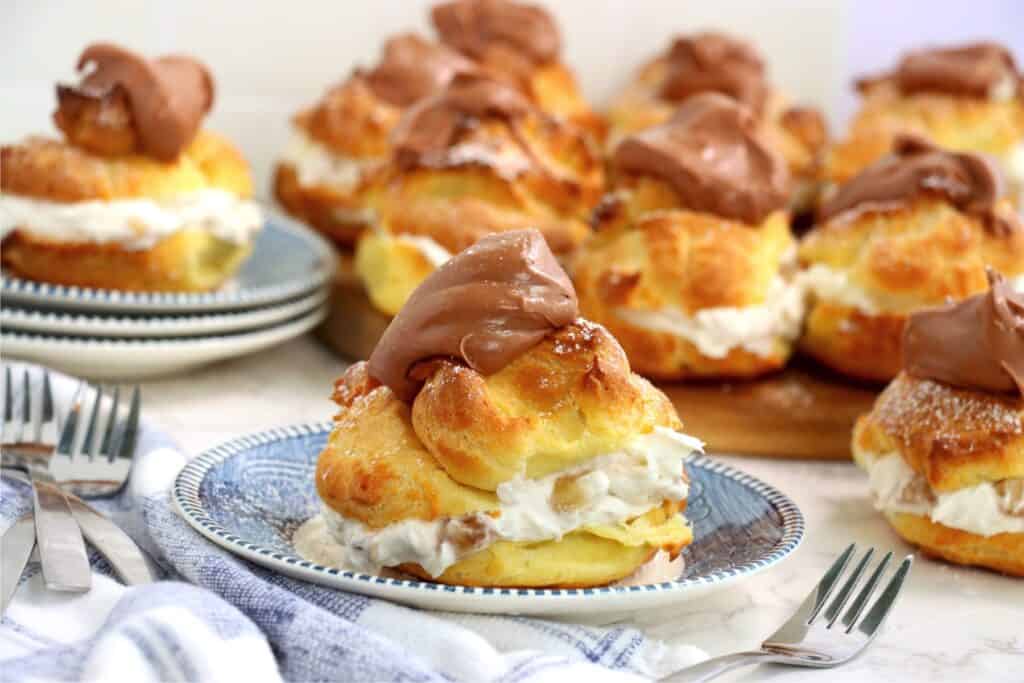 Closeup shot of banana cream puff on plate with more banana cream puffs in background