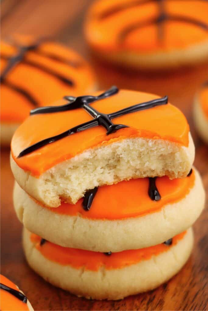 Closeup shot of basketball sugar cookies stacked atop one another with bite taken out of top cookie