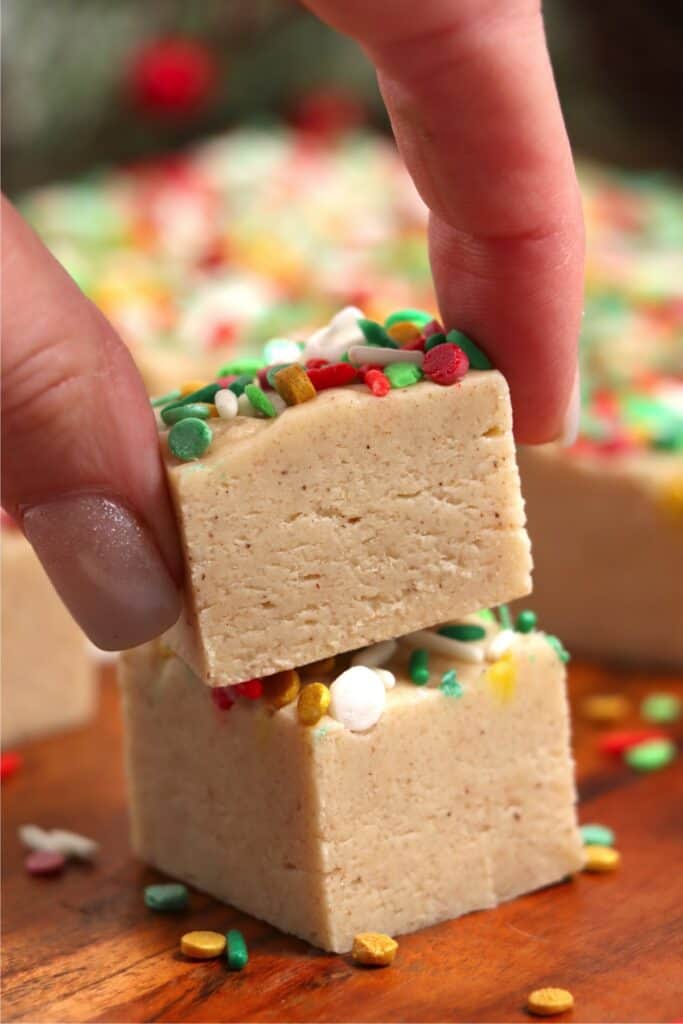 Closeup shot of hand stacking two pieces of Christmas cookie fudge atop one another. 