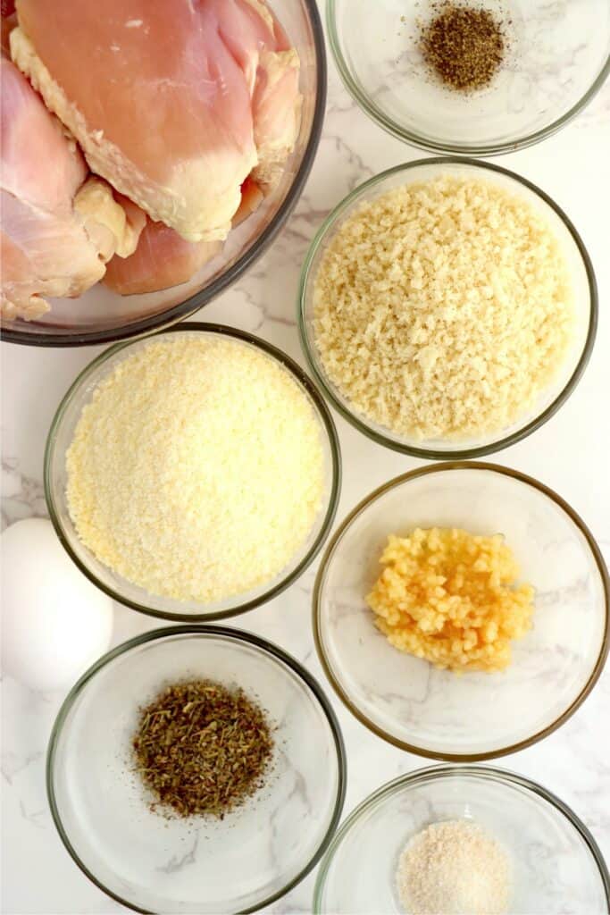 Overhead shot of individual garlic parmesan chicken ingredients in bowls on table