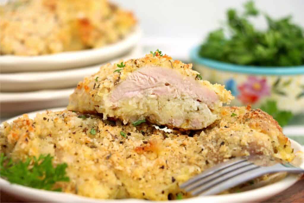 Closeup shot of garlic parmesan chicken thighs on plate with one thigh cut in half.