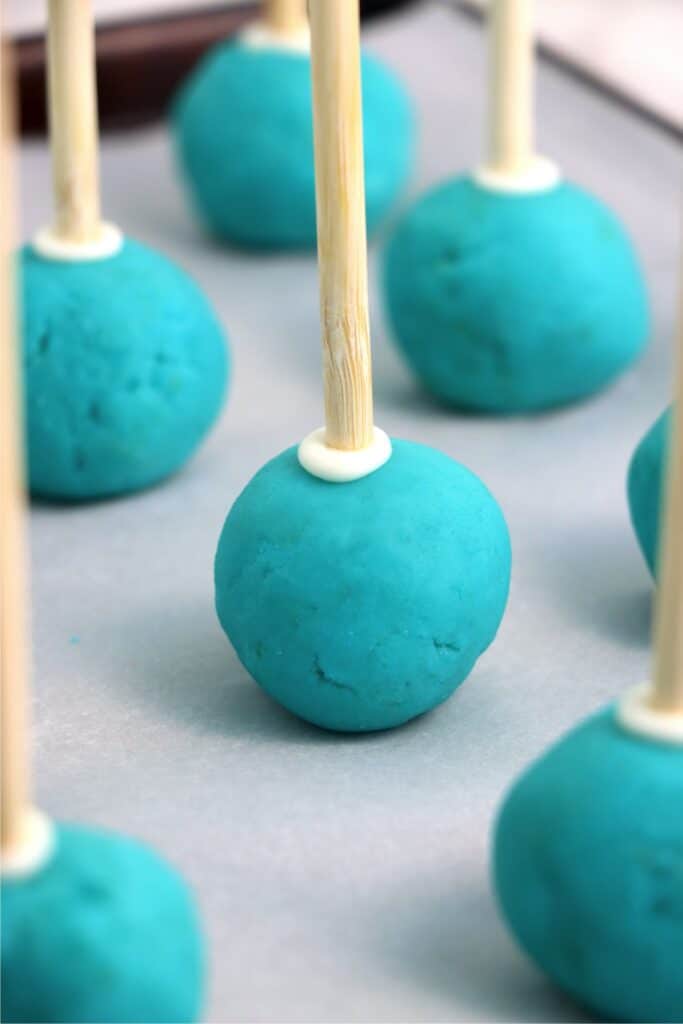 Unfrosted gender reveal cake pops on baking sheet lined with parchment paper