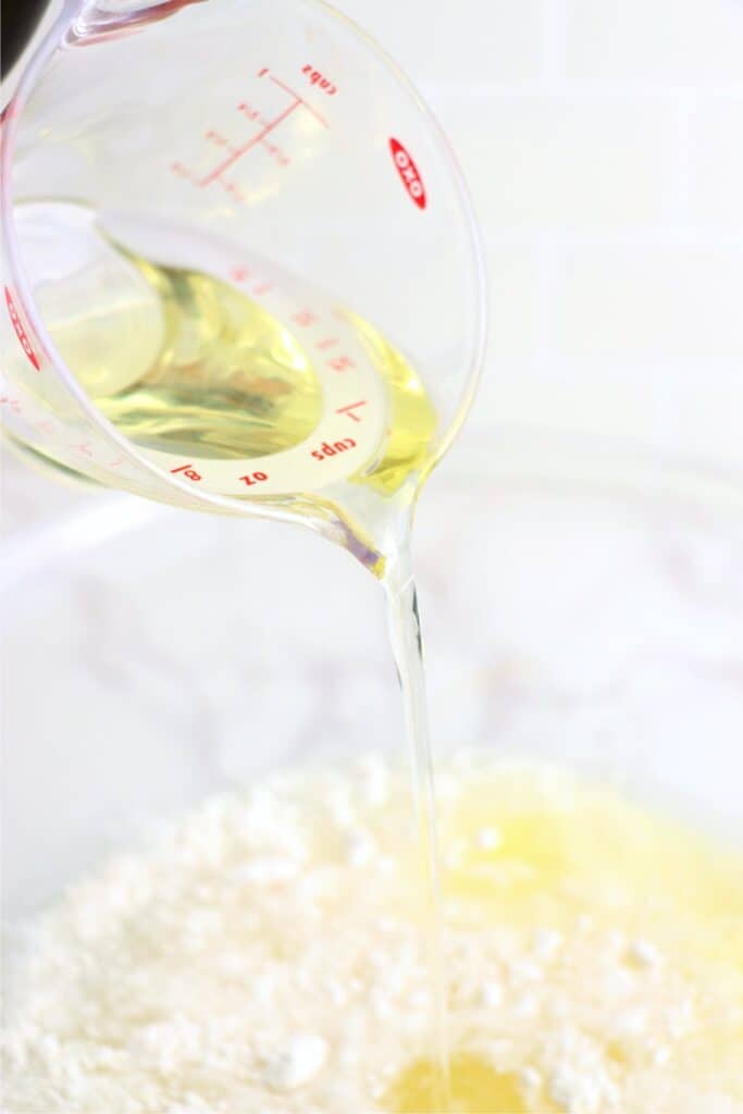 Closeup shot of oil being poured into mixing bowl with cake mix