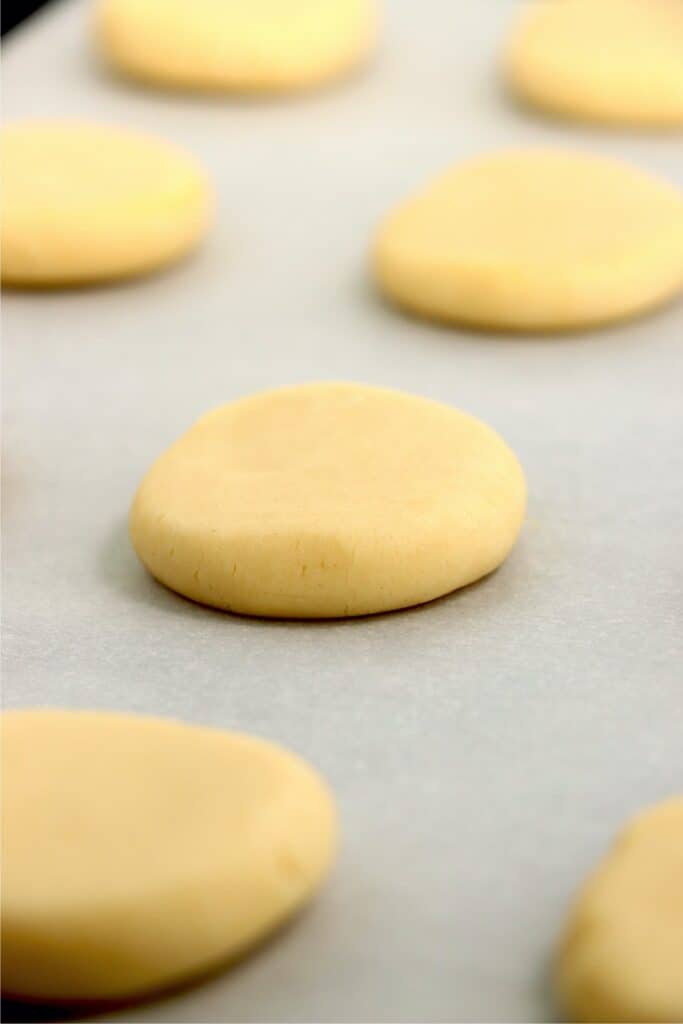 Closeup shot of unbaked sugar cookies on cookie sheet lined with parchment paper