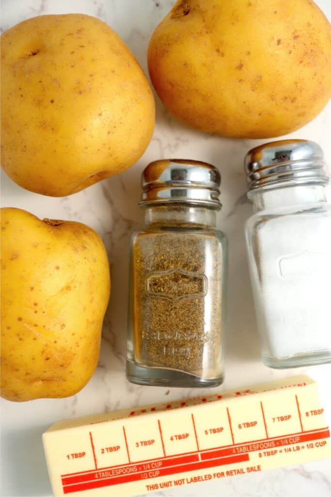 Cloesup overhead shot of potatoes, stick of butter, and salt and pepper shakers on table