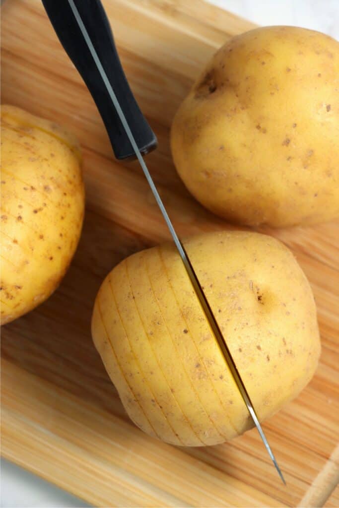 Overhead shot of knife cutting slits into potato