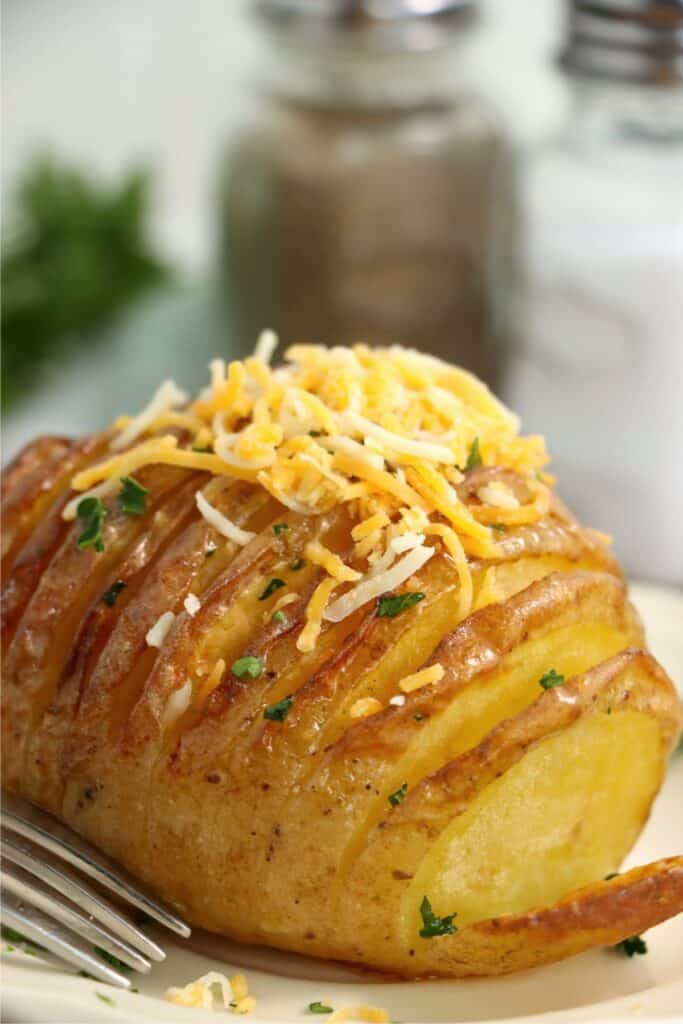 Closeup shot of air fryer Hasselback potato topped with cheese.