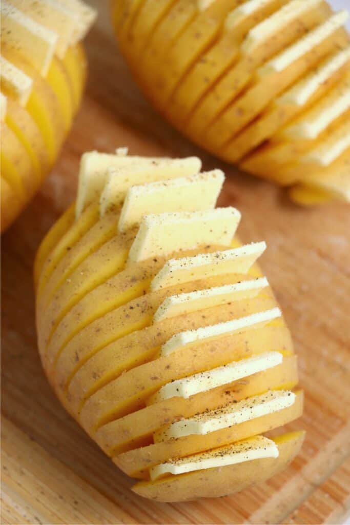 Closeup shot of potatoes with butter pats placed between each slit cut into them